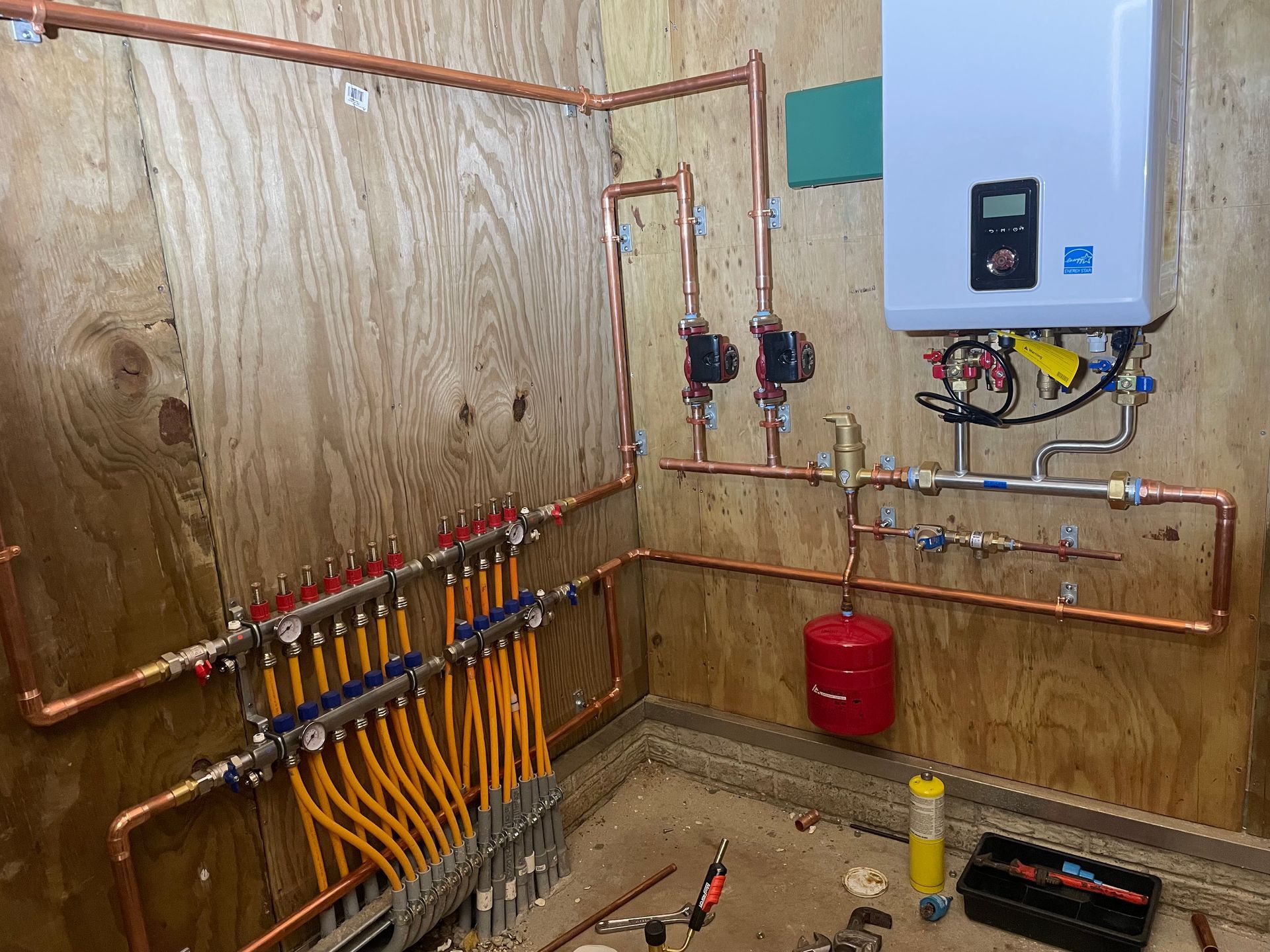 Copper pipes and radiant heating system installed on a wooden wall.