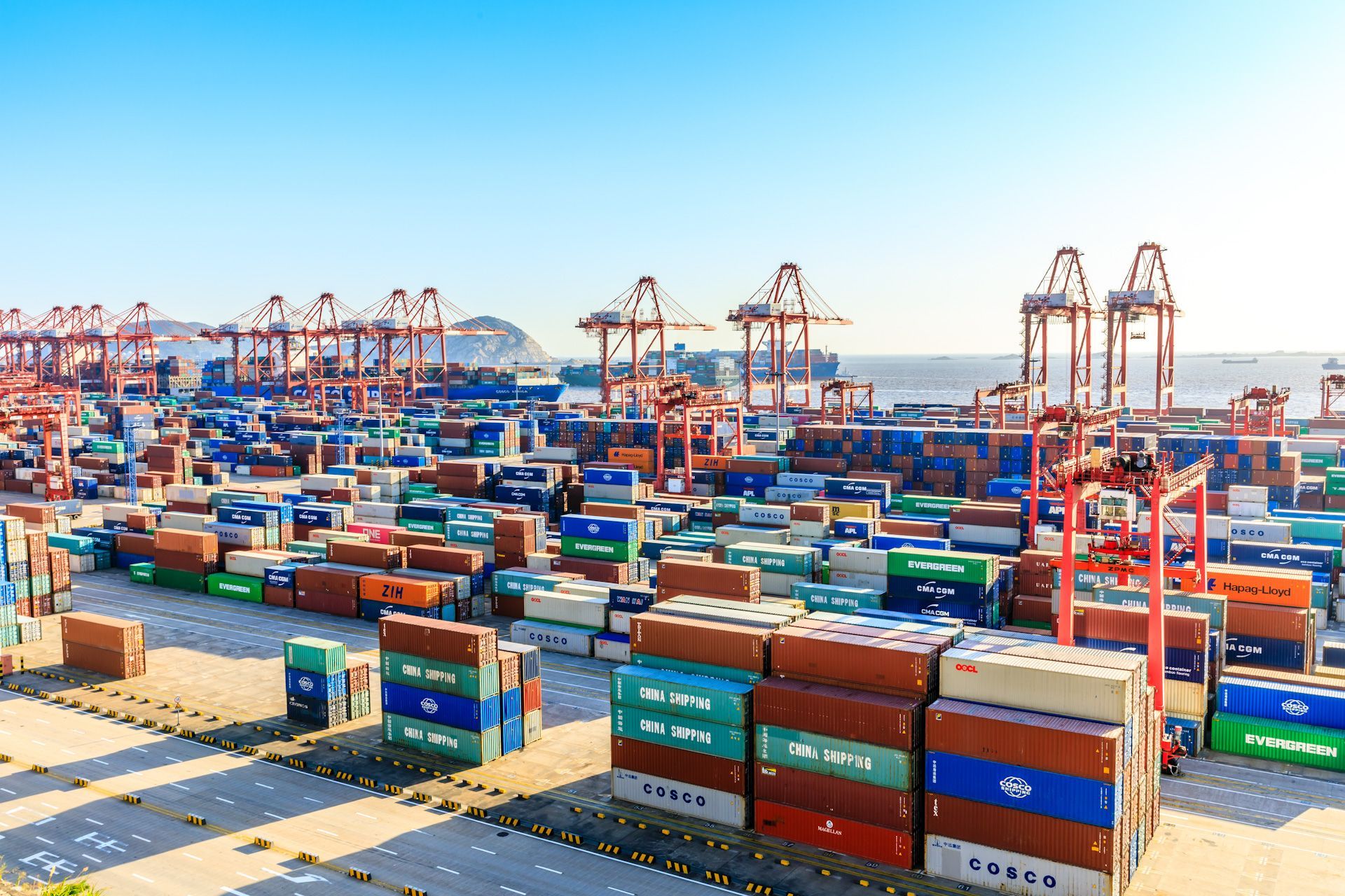 A large warehouse filled with lots of shipping containers and cranes.