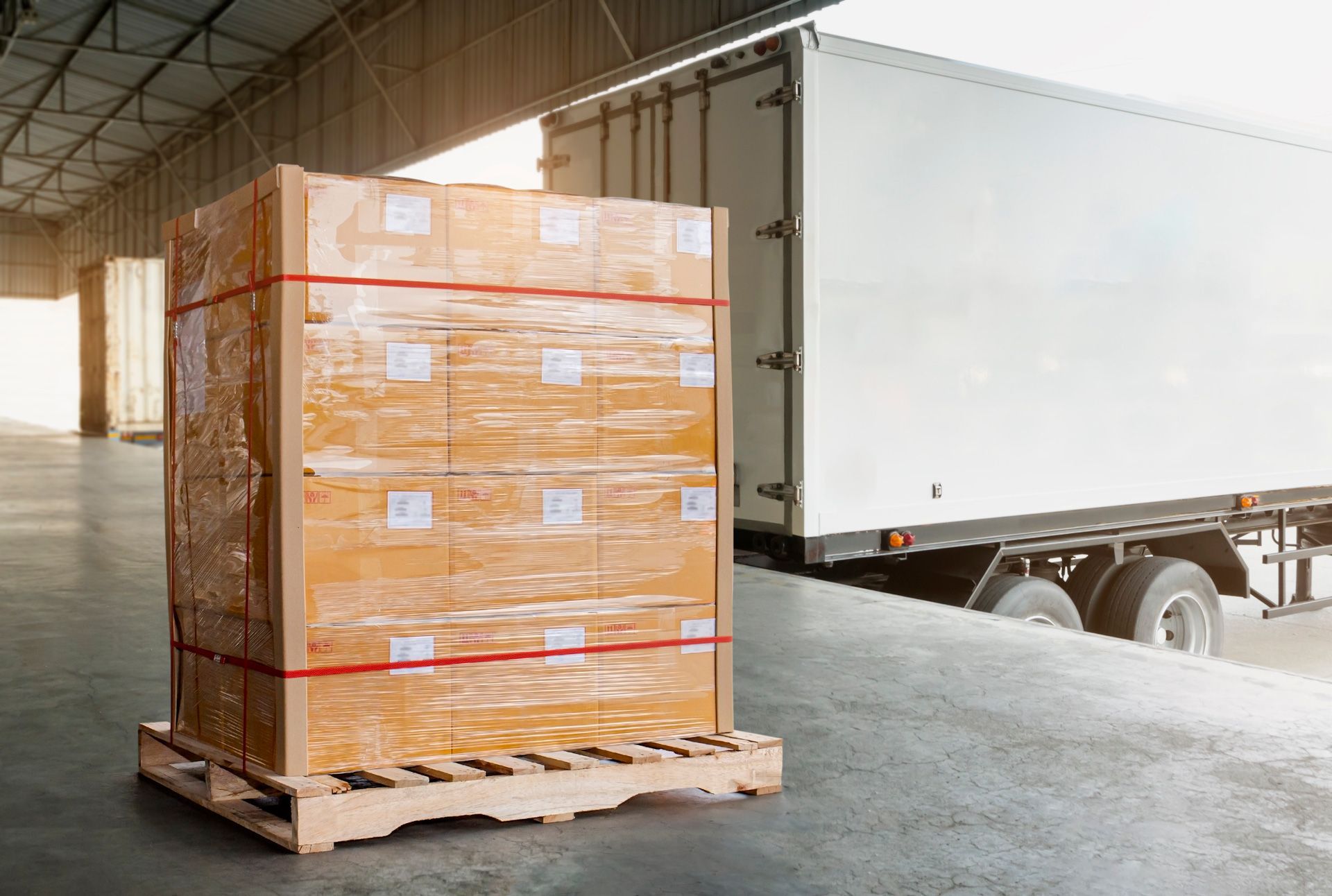 A truck is loading boxes on a wooden pallet in a warehouse.