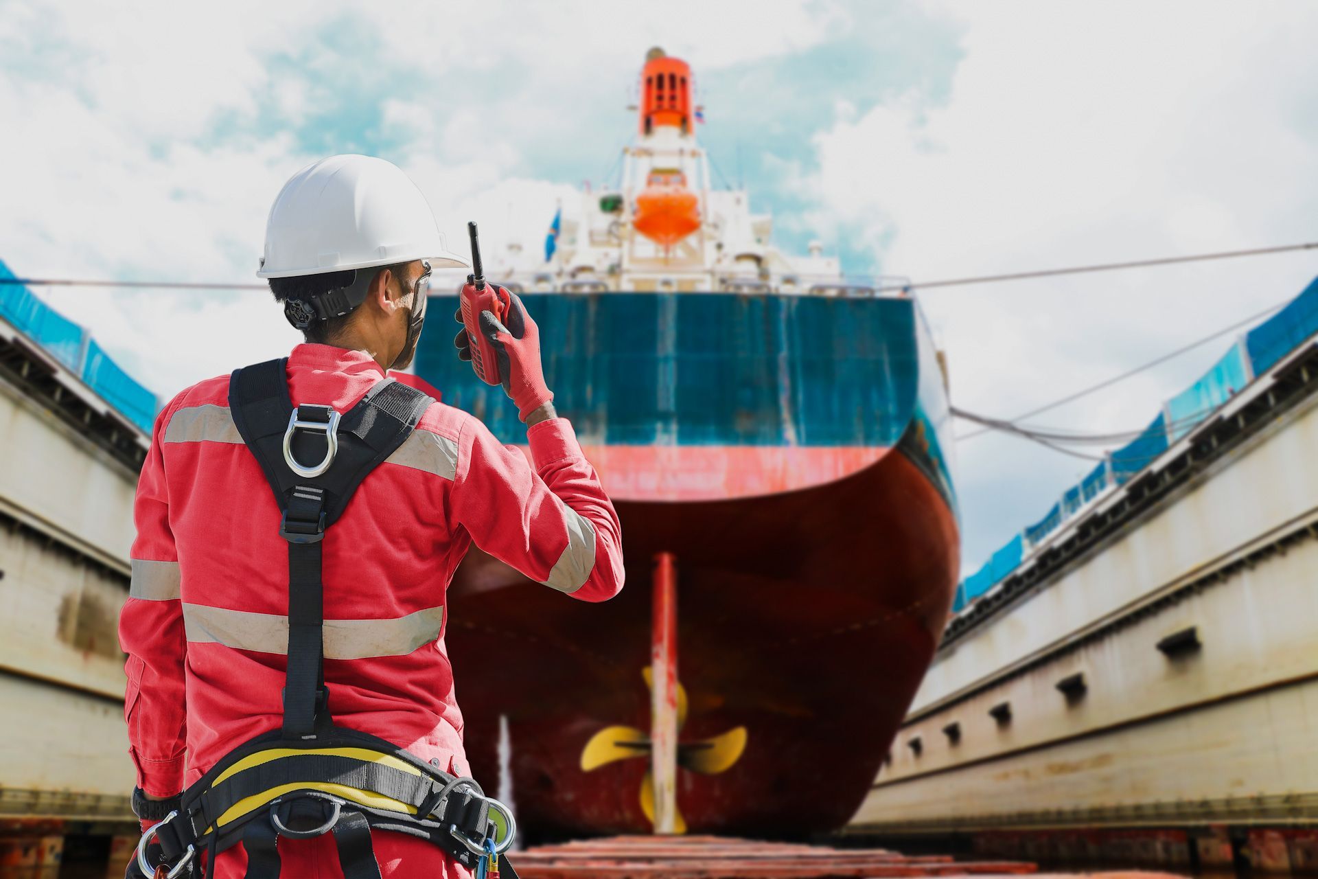 A man is talking on a walkie talkie in front of a large ship.