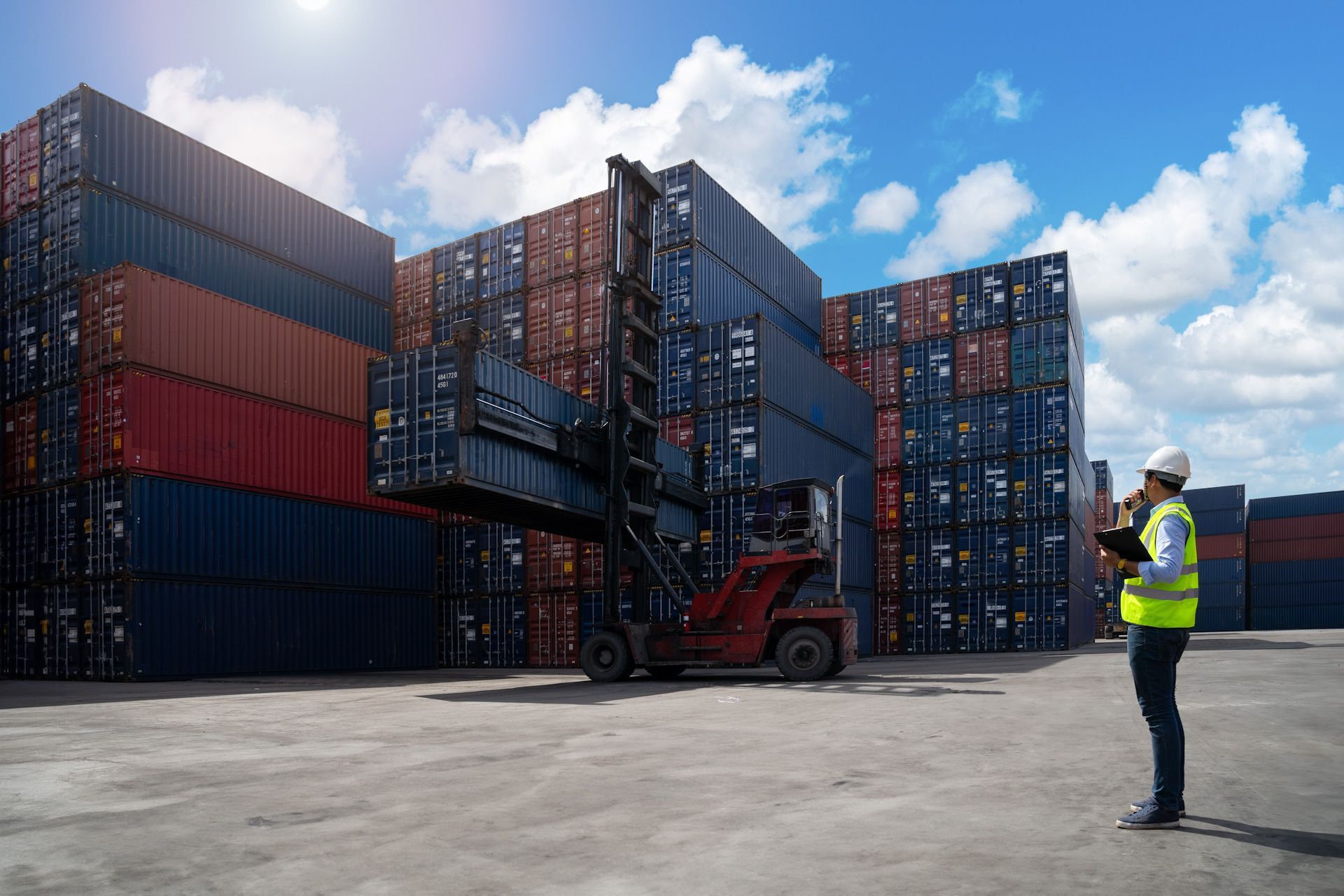 A man is standing in front of a forklift in a warehouse.