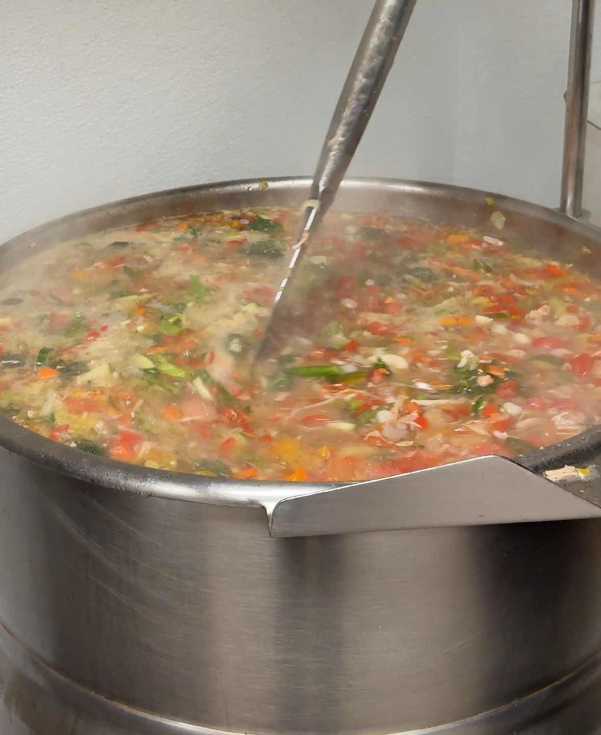 A person is pouring soup from a ladle into a cup