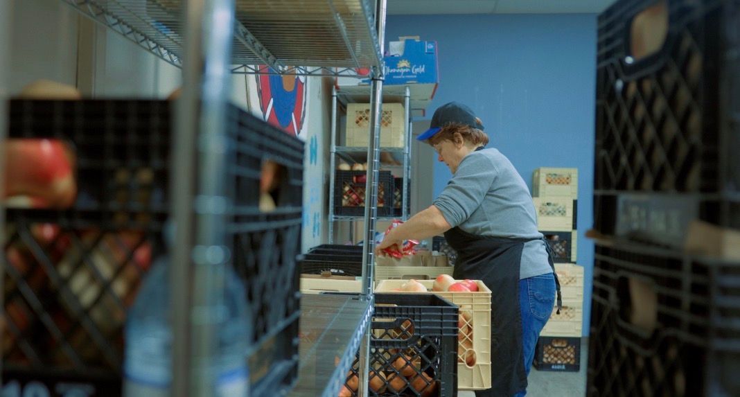 A man is pouring a cup of soup into a bowl.