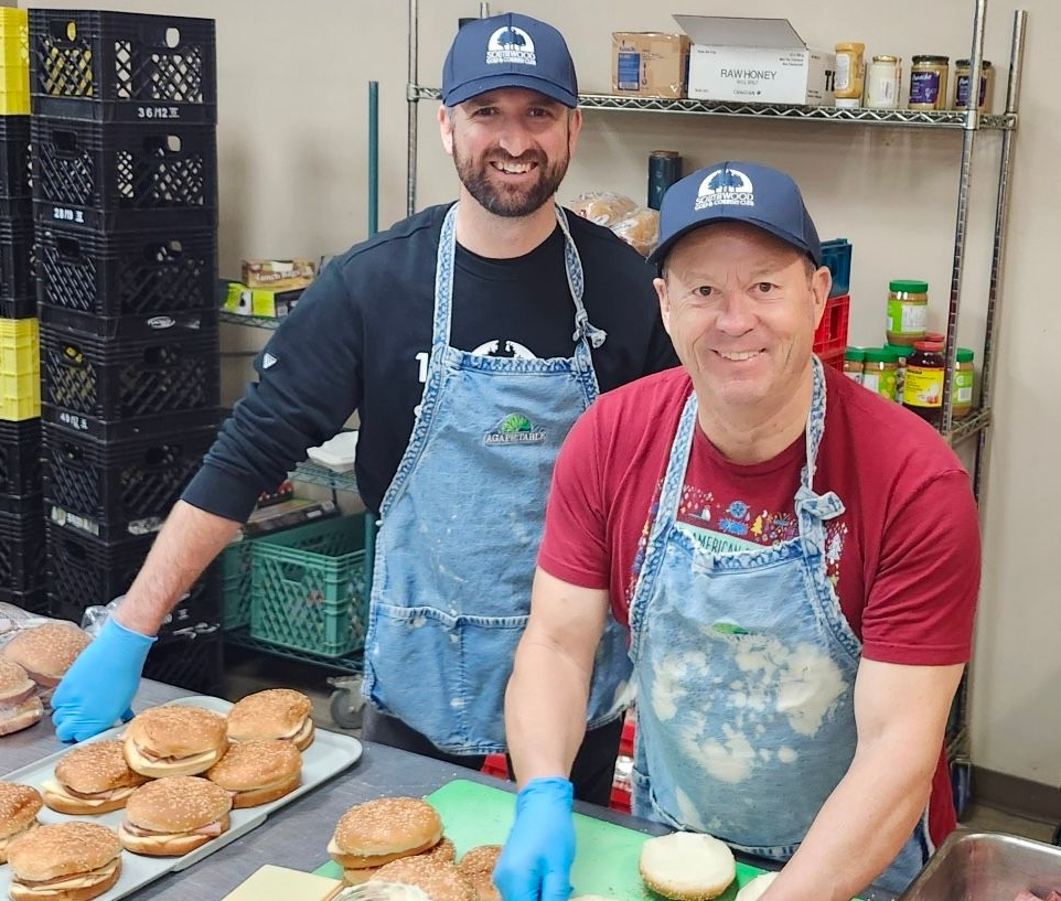 A man passing a bagged lunch to a person.