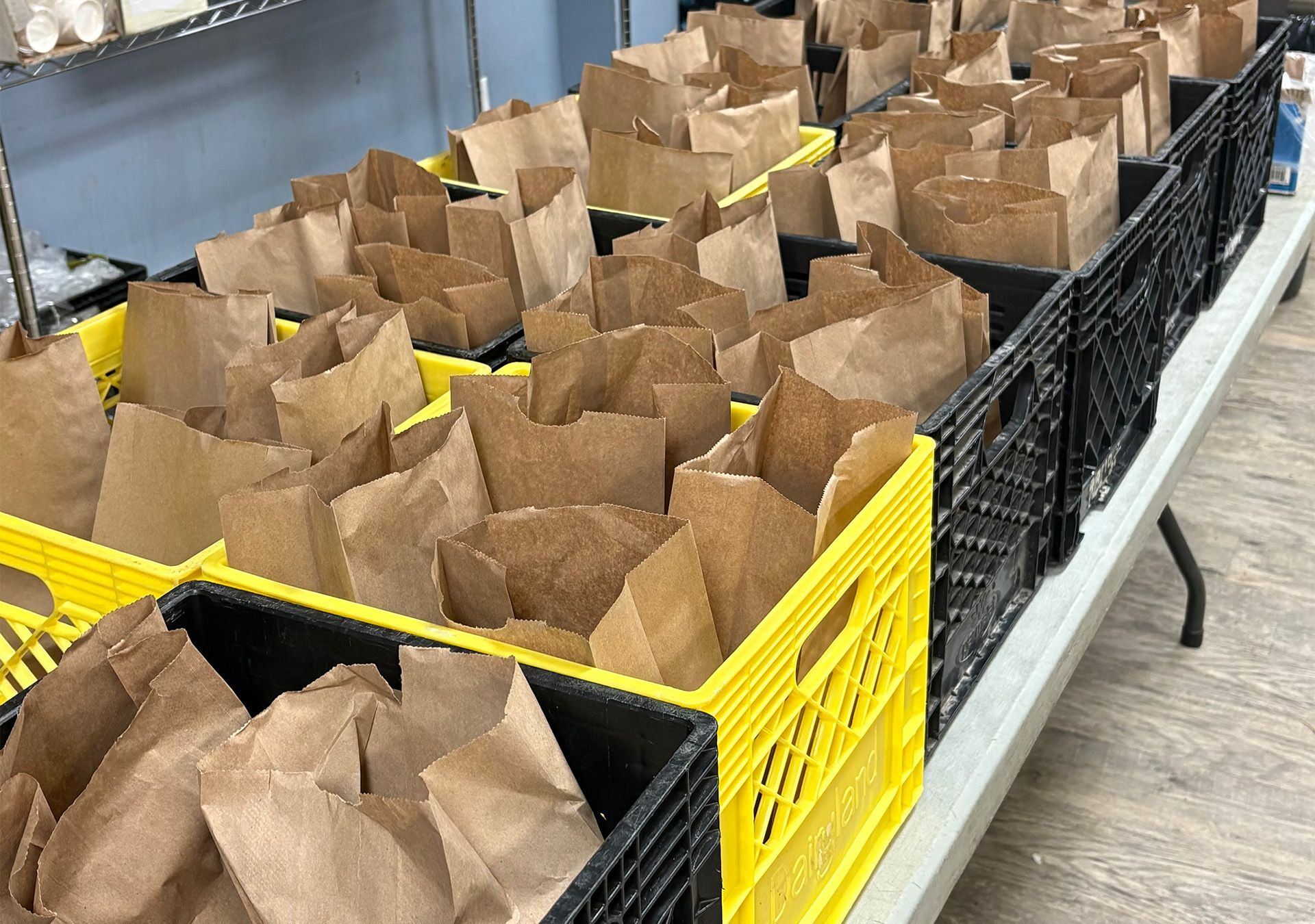 A bagged lunch including a banana, orange, sandwich, soup, eggs.