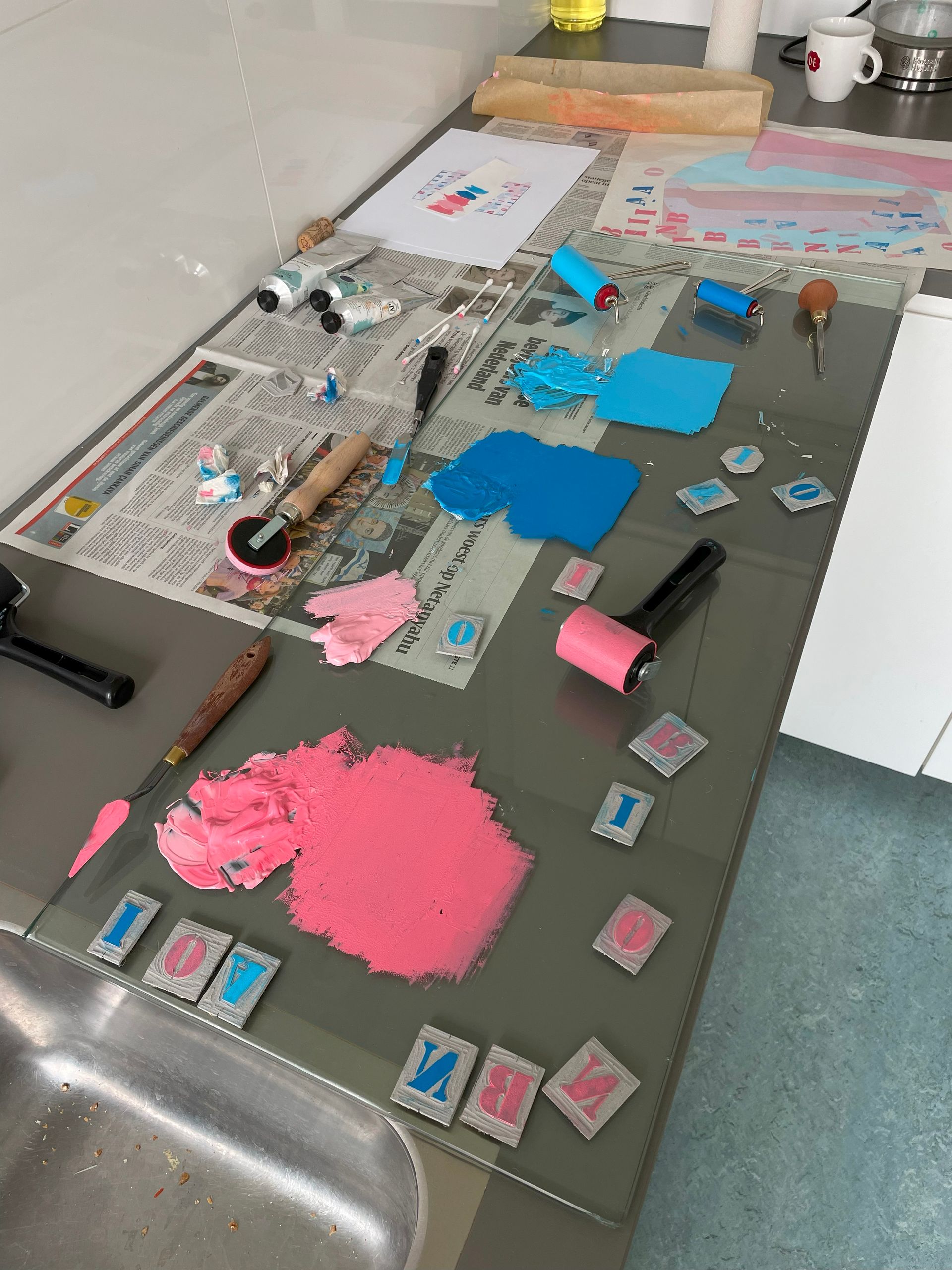Een aanrecht met roller in roze en blauwe verf erop