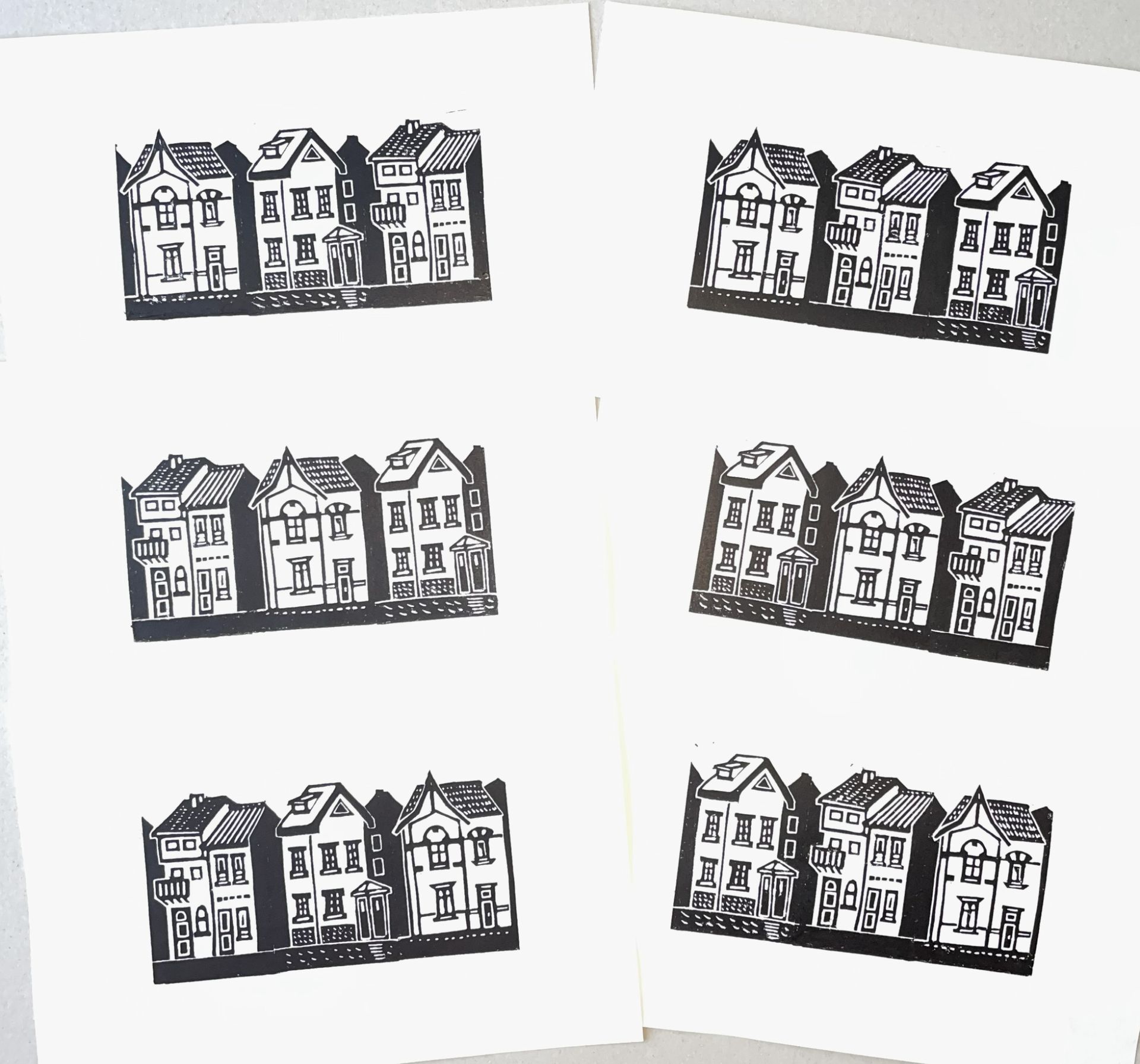 Een collage van zes zwart-wit houtsneden, die elk een rij van drie gestileerde huizen in Europese stijl tonen.