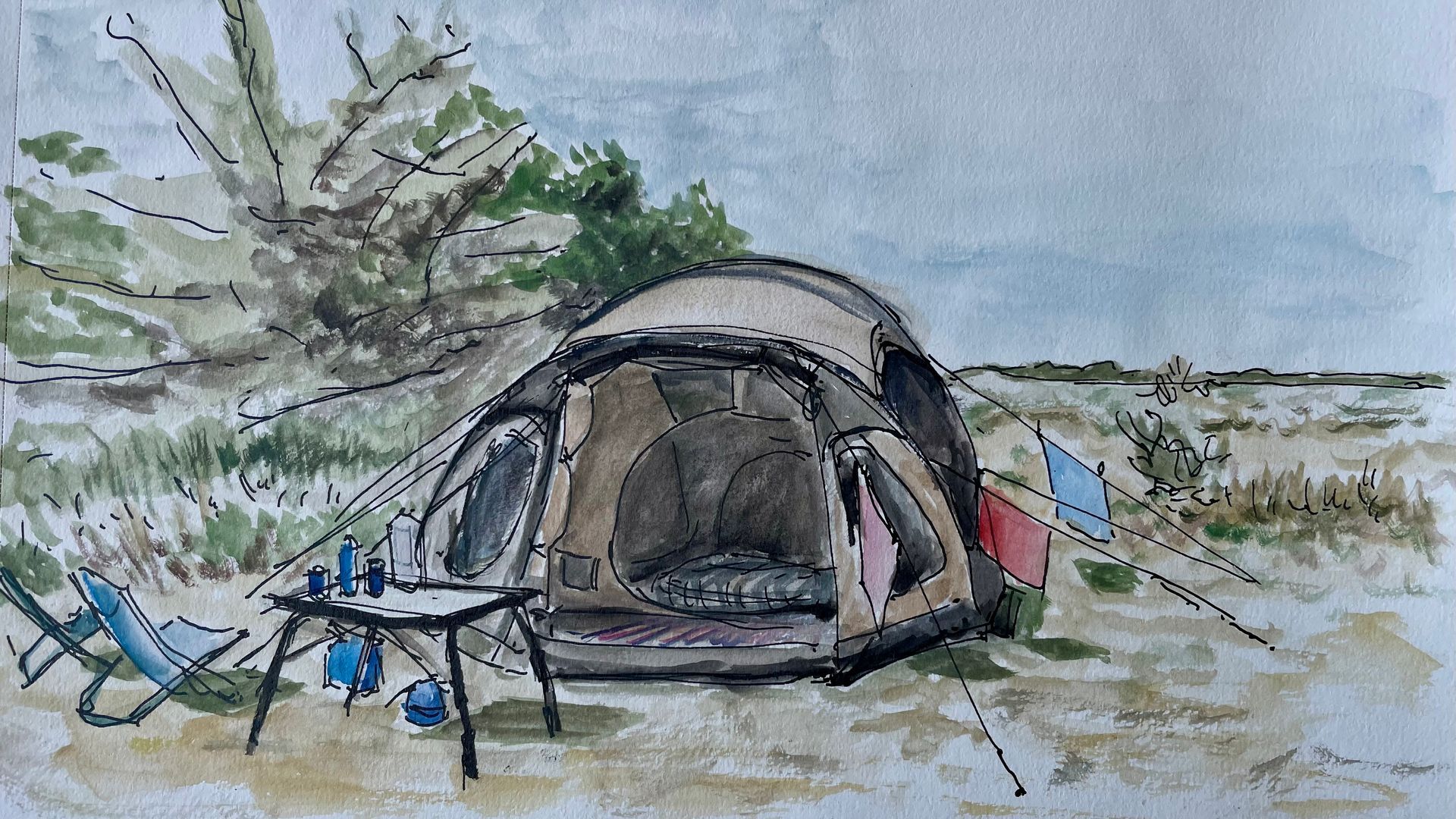 Een kampeertent met tafel, stoelen en kampeerspullen staat opgesteld op een zandstrand onder een bewolkte hemel.