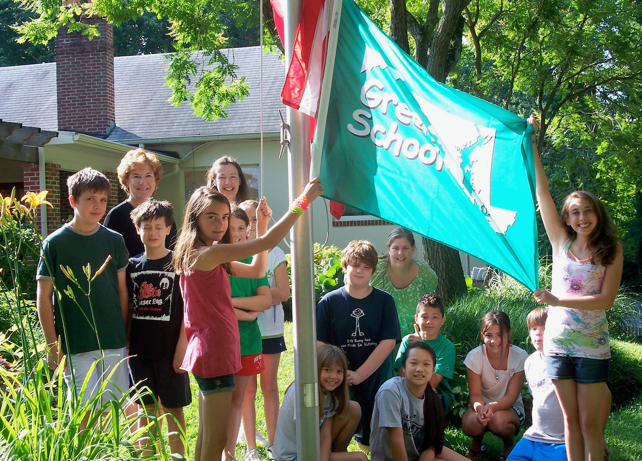 A group of Montessori children holding a green school flag