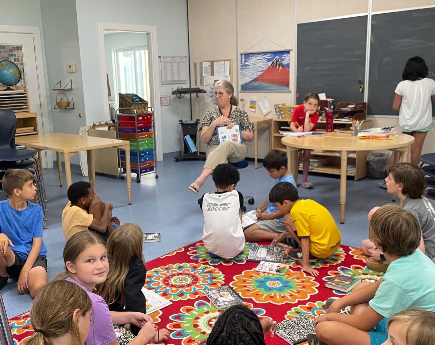 Upper Elementary guide and a group of child working in the classroom 