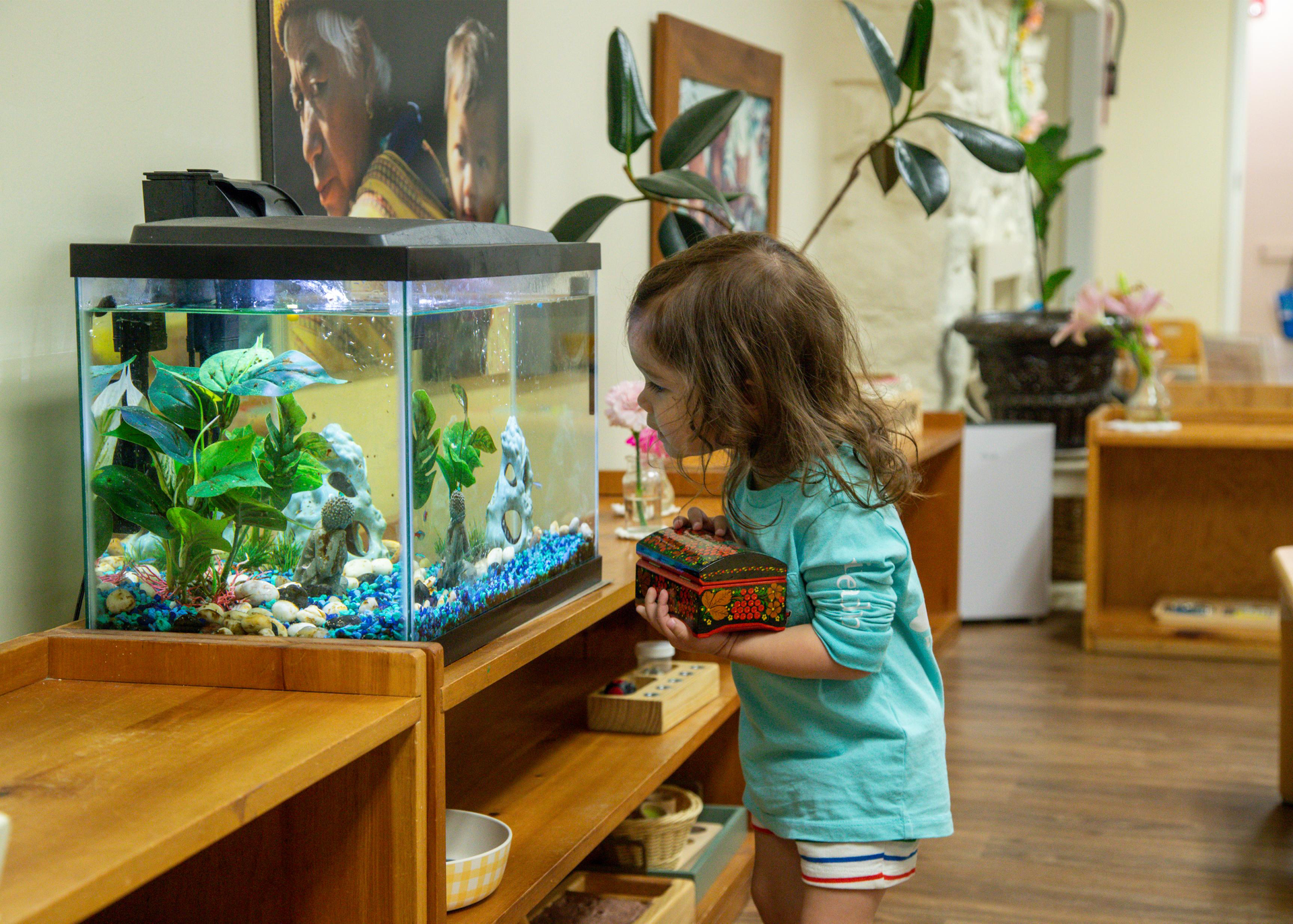 A little girl is looking at a fish tank in a room.