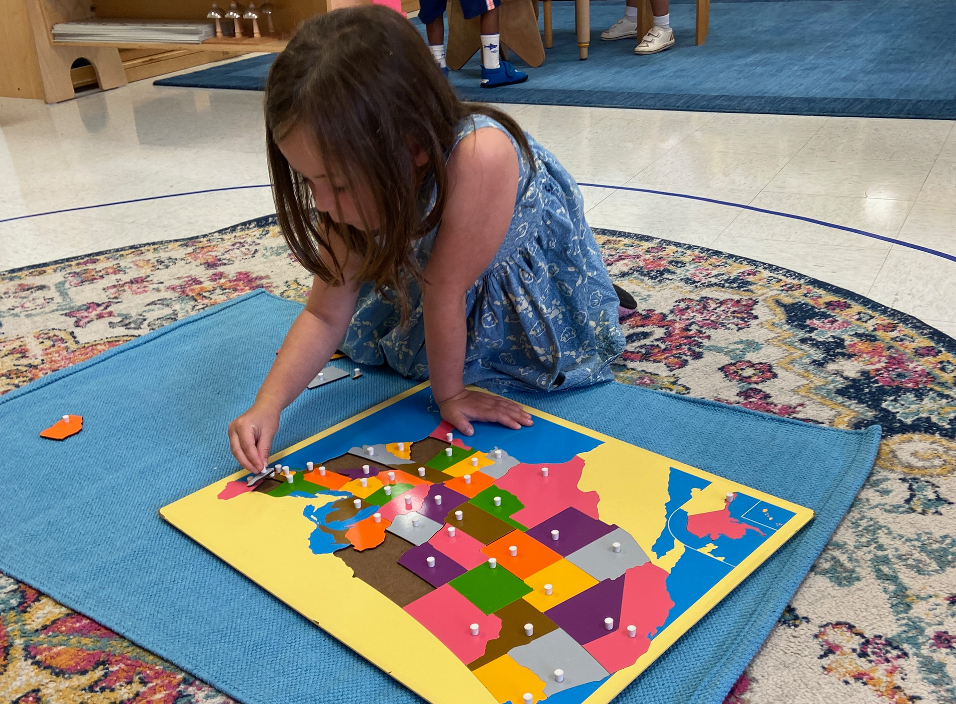 Montessori girl is playing with a map of the united states.