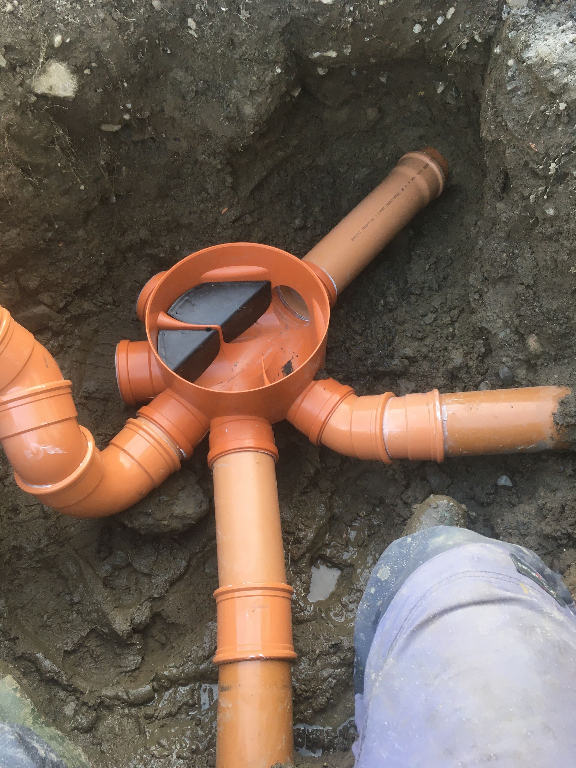 A person is standing next to a bunch of pipes in the dirt.