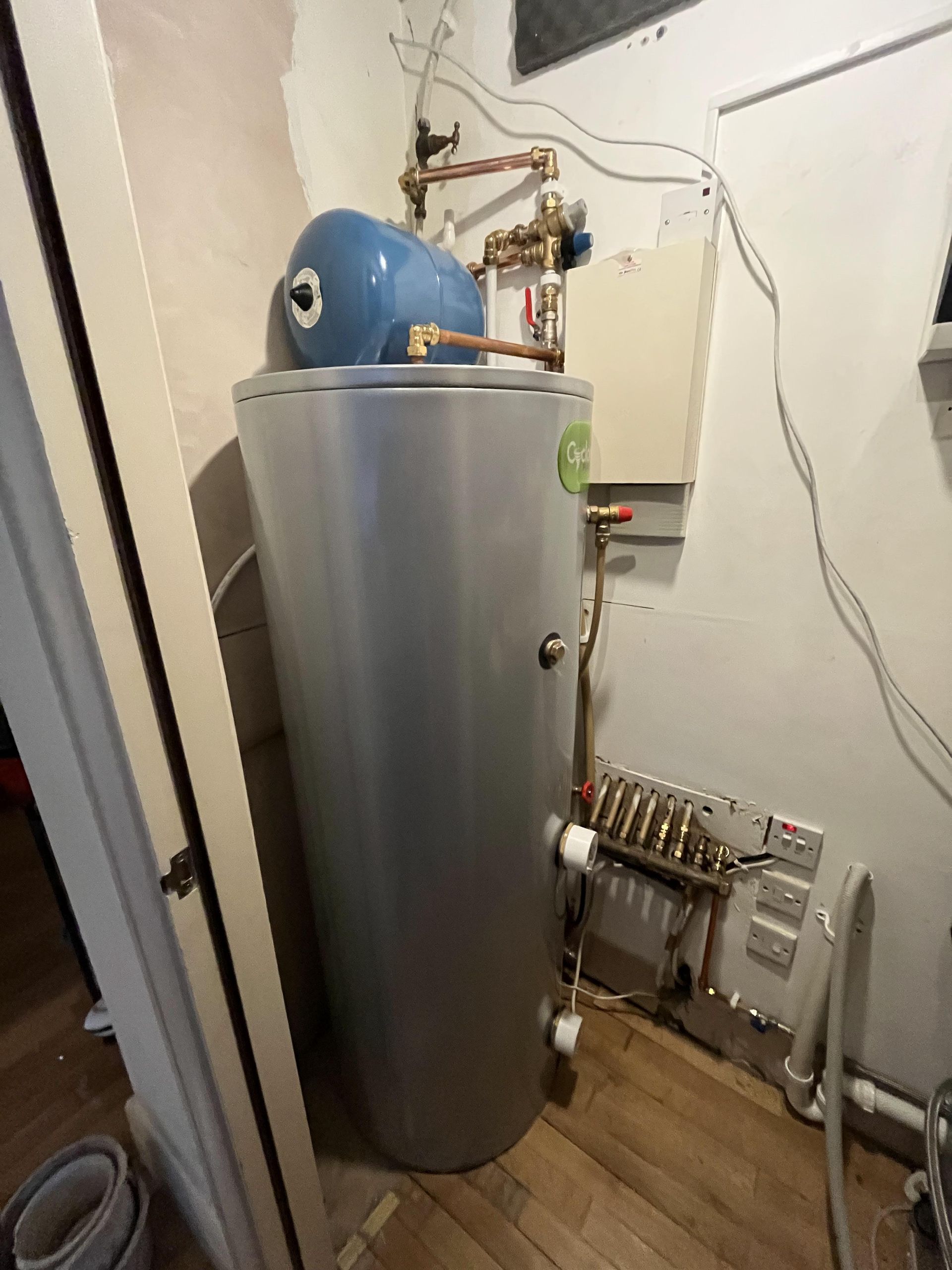 A water heater is sitting in a room next to a door.