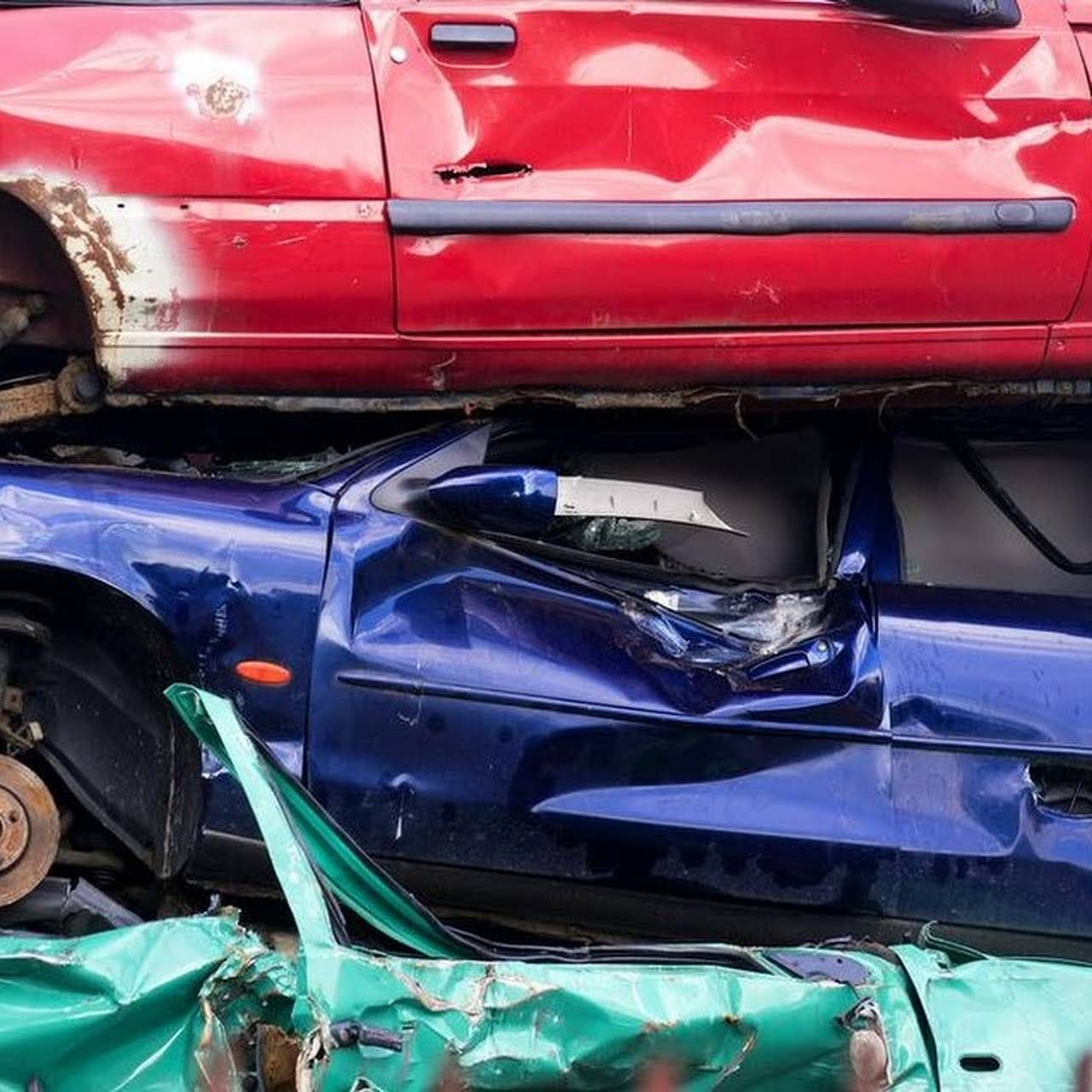 A Red Car On Top Of A Blue Car On Top Of A Green Car Getting Crushed — Old Bar Wreckers In Hallidays Point, NSW