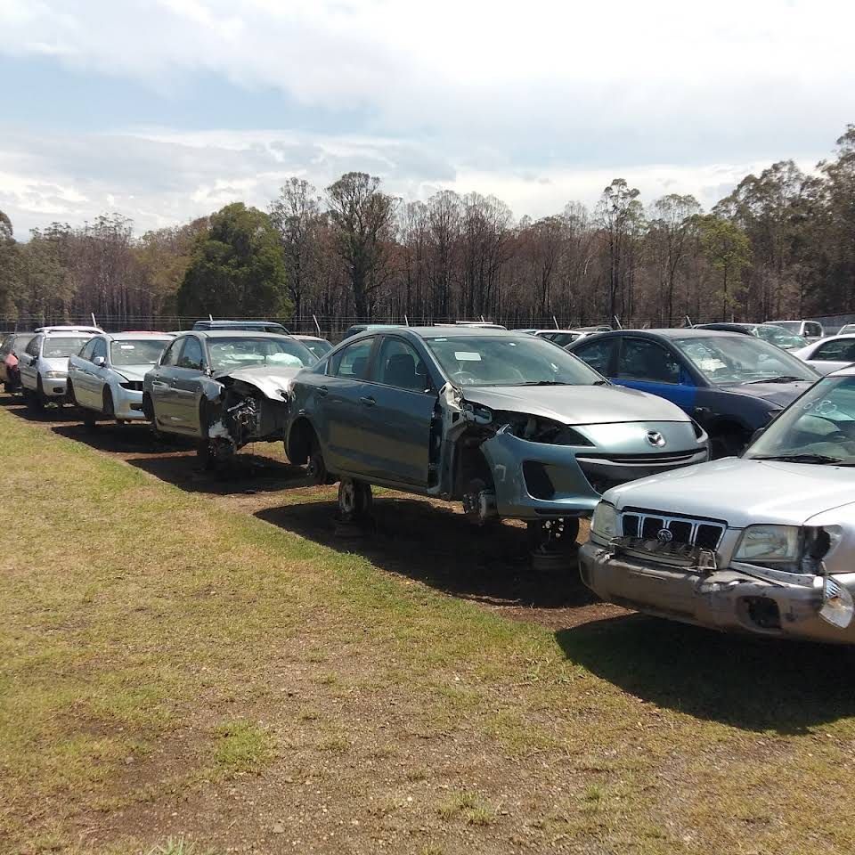 A White Boat Is Sitting On A Trailer In The Grass — Old Bar Wreckers In Glenthorne, NSW