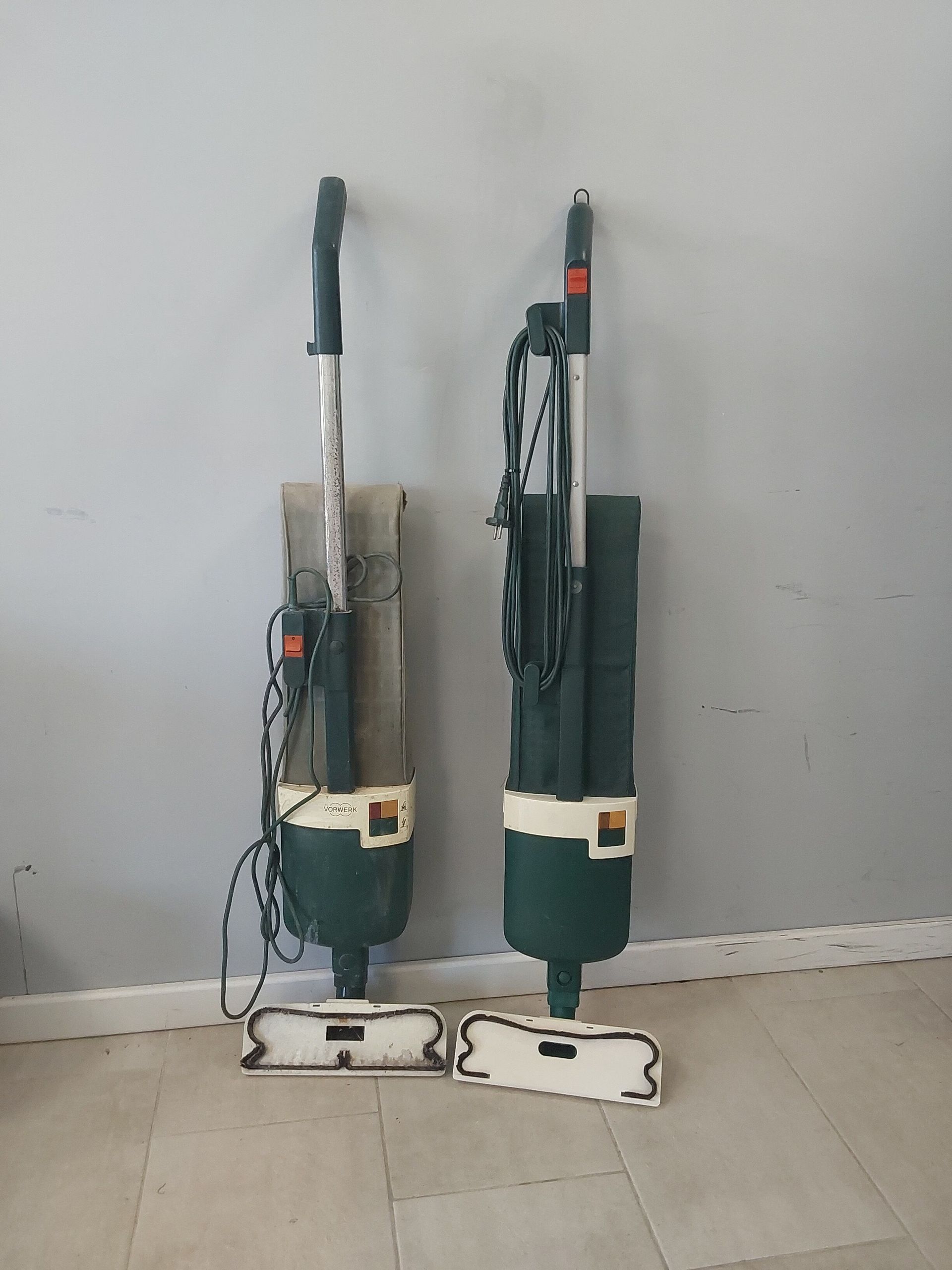 Due aspirapolvere sono posizionati uno accanto all'altro su un pavimento piastrellato.