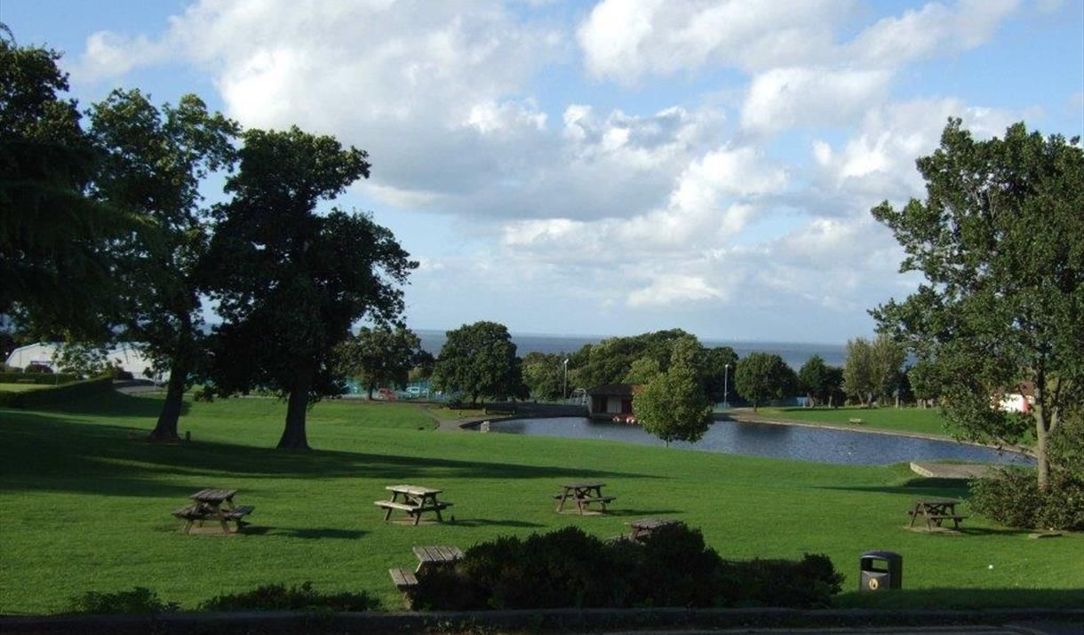 a picnic area in a park with a lake in the background