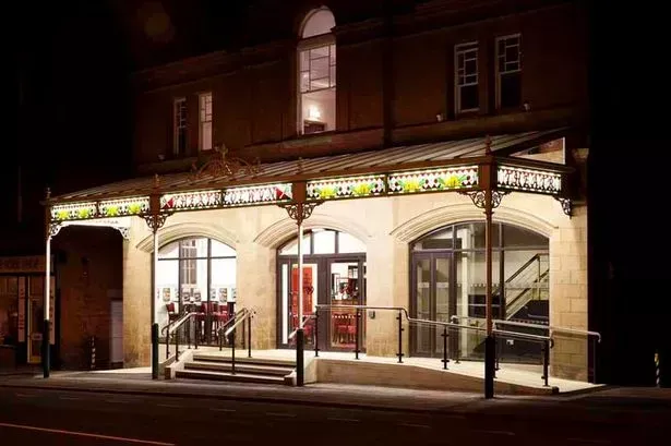 a large building with a canopy over the entrance is lit up at night .