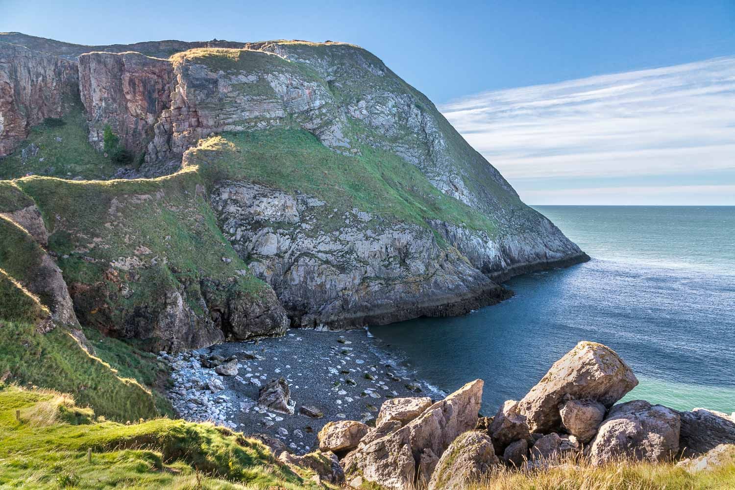 a cliff overlooking the ocean with a large body of water in the background .