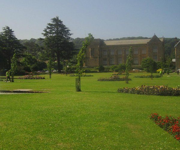 a large building is behind a lush green field .