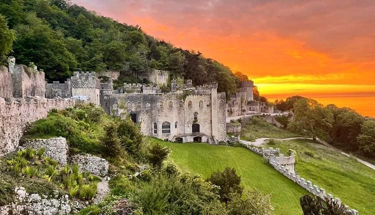 A castle on top of a hill with a sunset in the background.