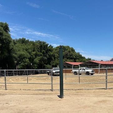 A white truck is parked in a dirt field behind a fence.