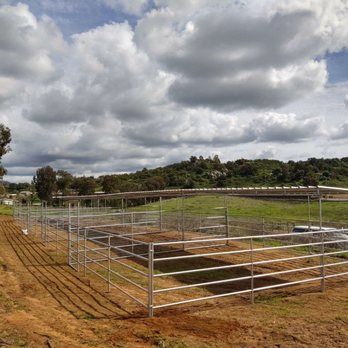 There is a fence in the middle of a field with a cloudy sky in the background.