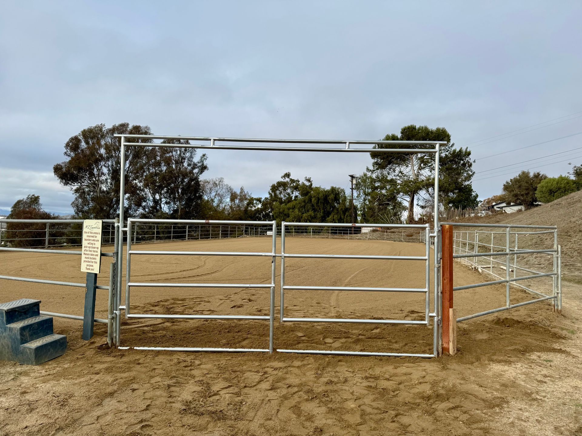 A metal gate is sitting in the middle of a dirt field.