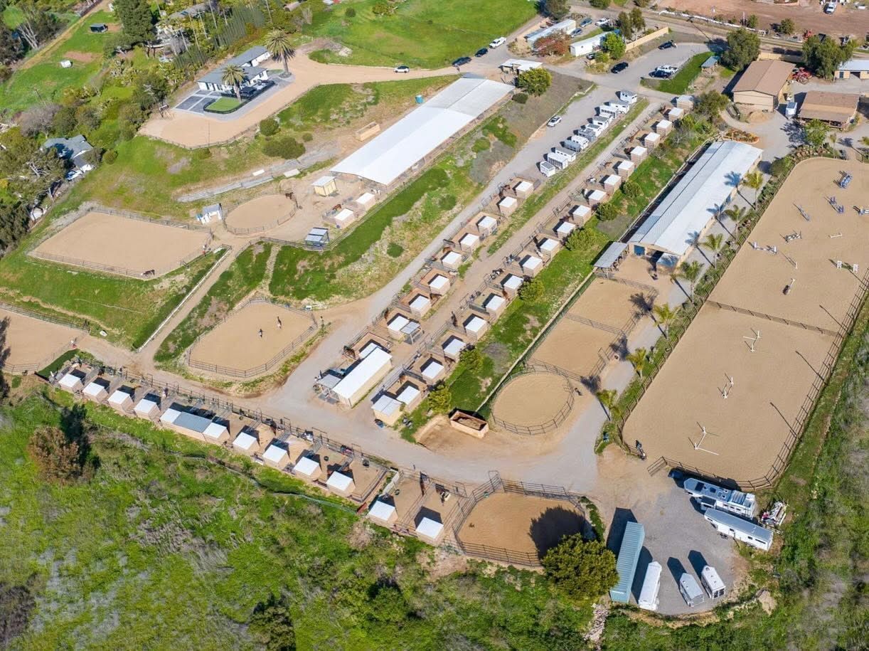 An aerial view of a horse ranch with lots of buildings and fields.