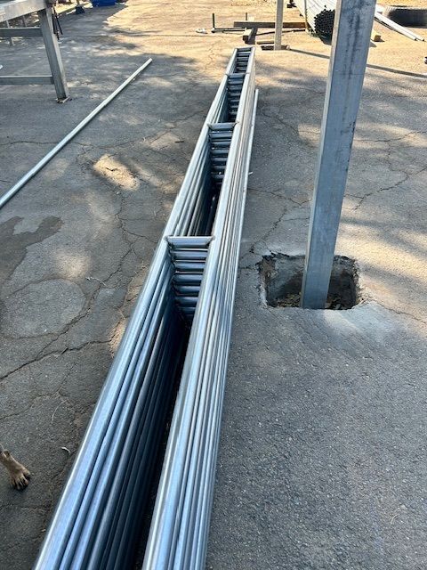 A row of metal pipes are stacked on top of each other on the ground.