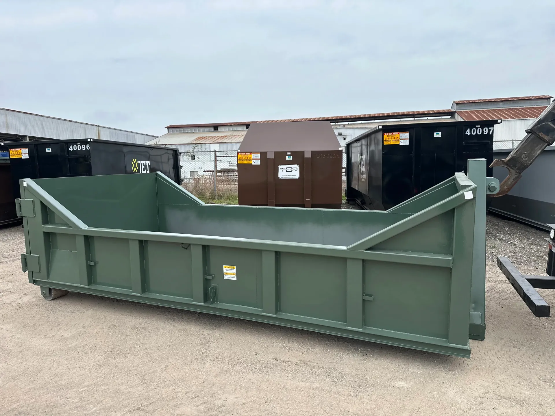 A dump truck with a green dumpster attached to it is parked in a parking lot.