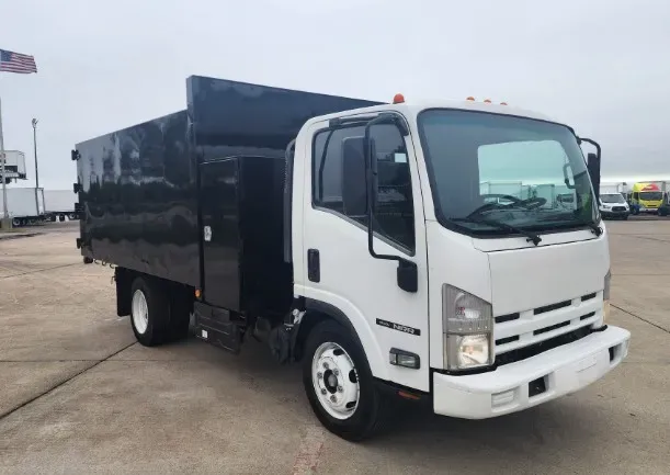 A white dump truck with a black bed is parked in a parking lot.