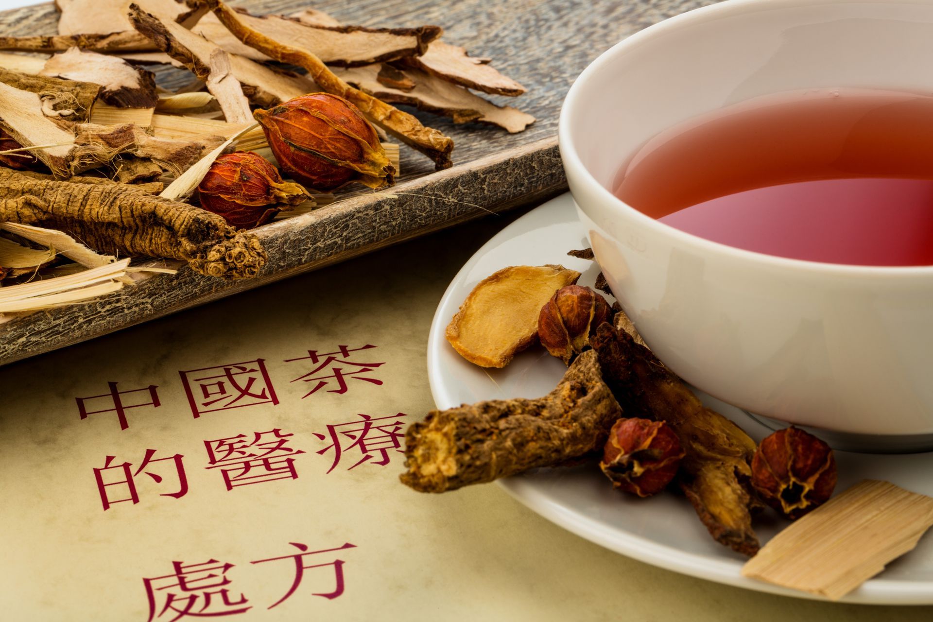 Traditionelle chinesische Heilkräuter neben einer Tasse Kräutertee auf einer Seite mit chinesischem Text