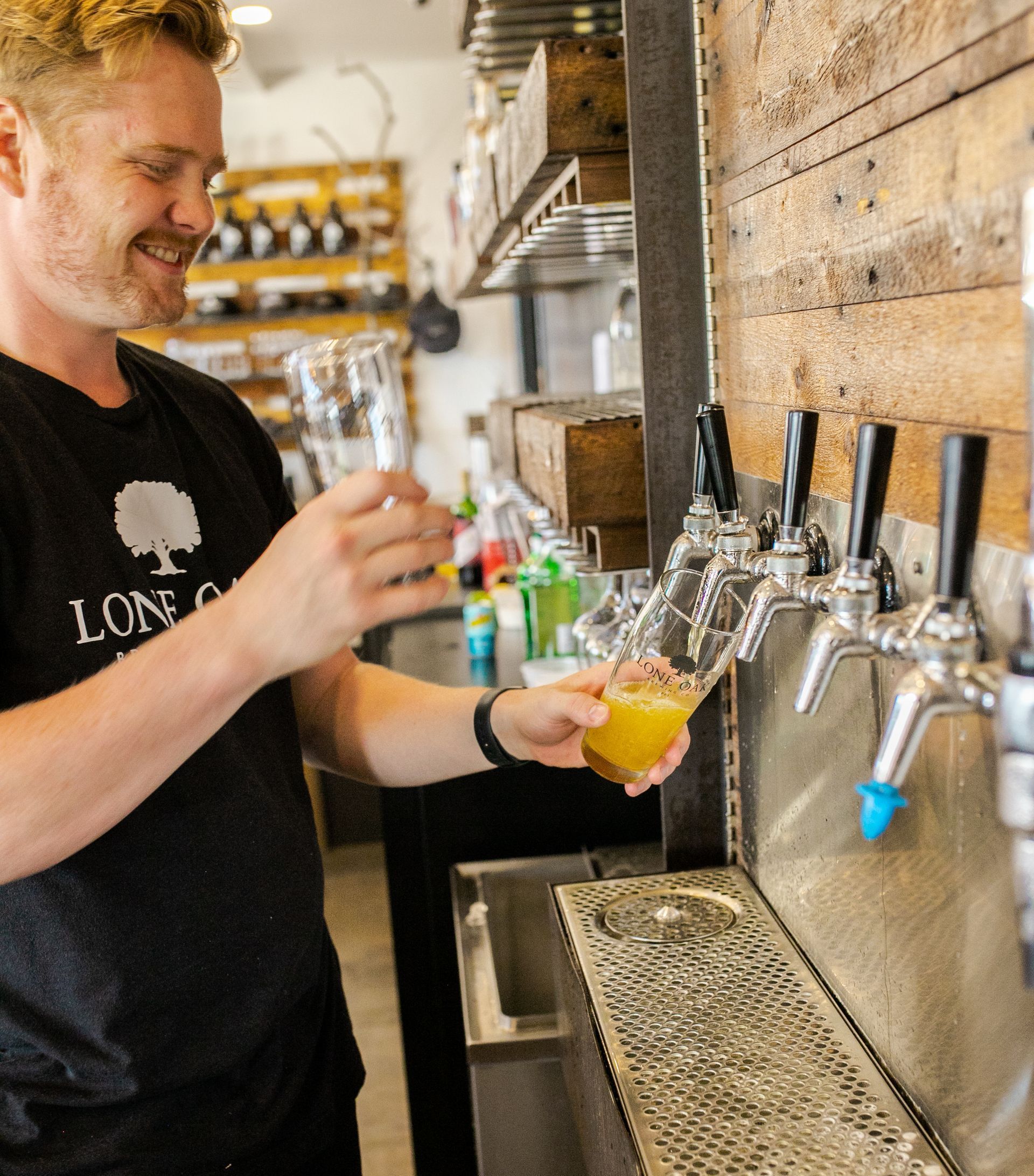 Bartender pours beer from a tap at Lone Oak Brewing Company.