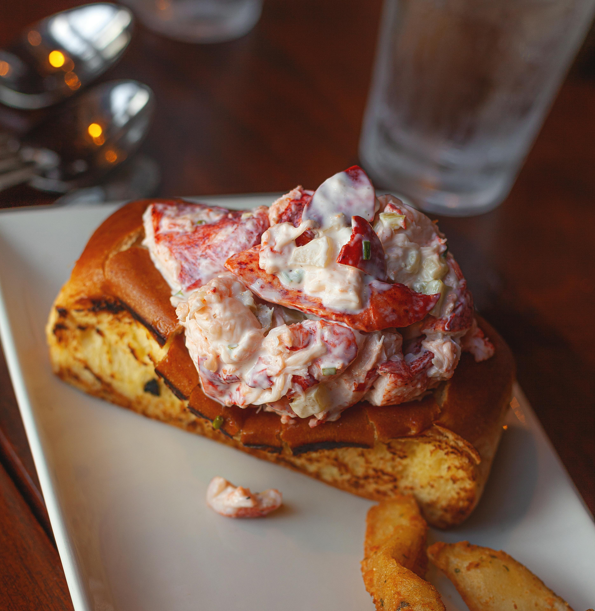 Lobster roll with a generous portion of lobster salad on a toasted bun, served on a white plate.