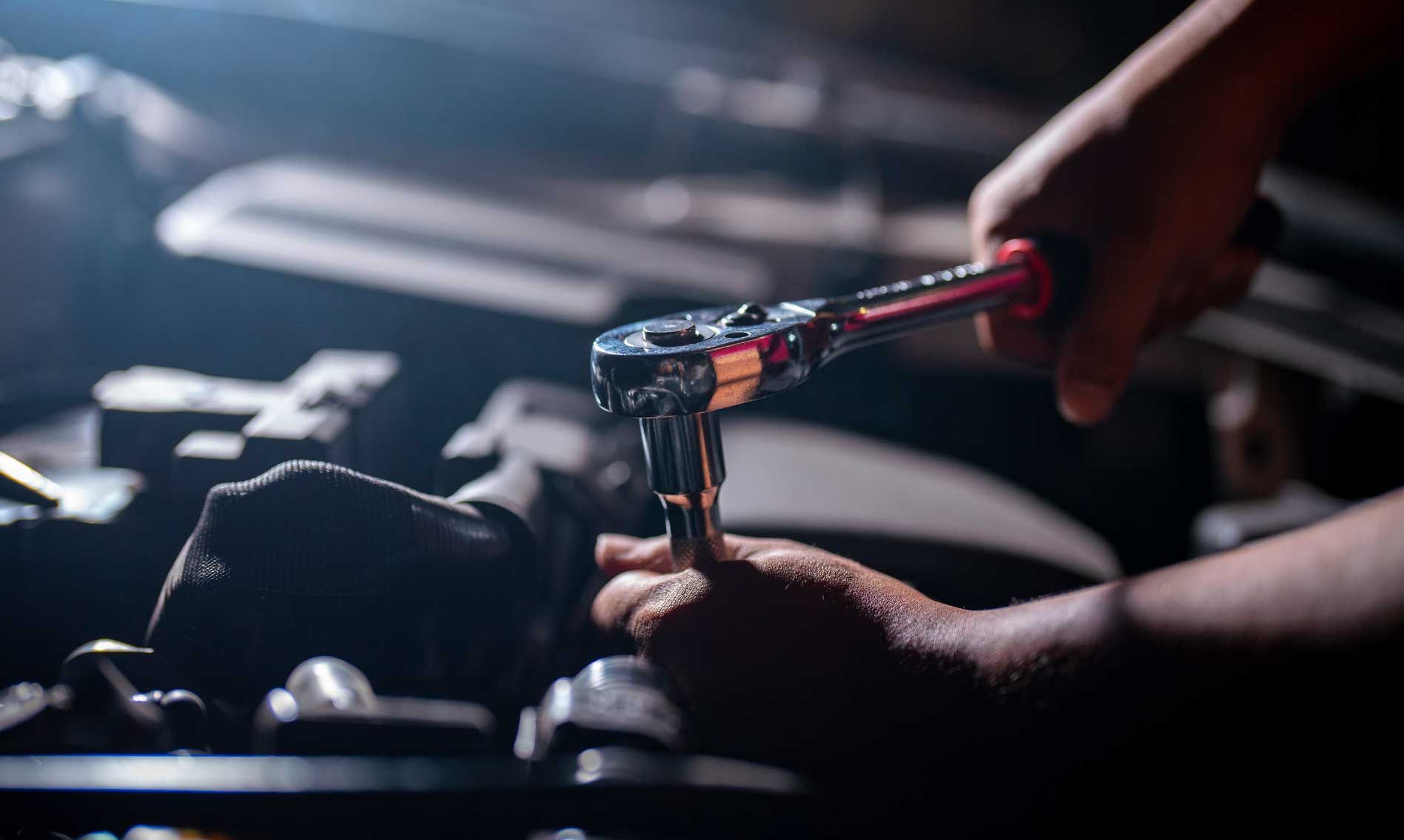 Auto mechanic working on car engine in mechanics garage