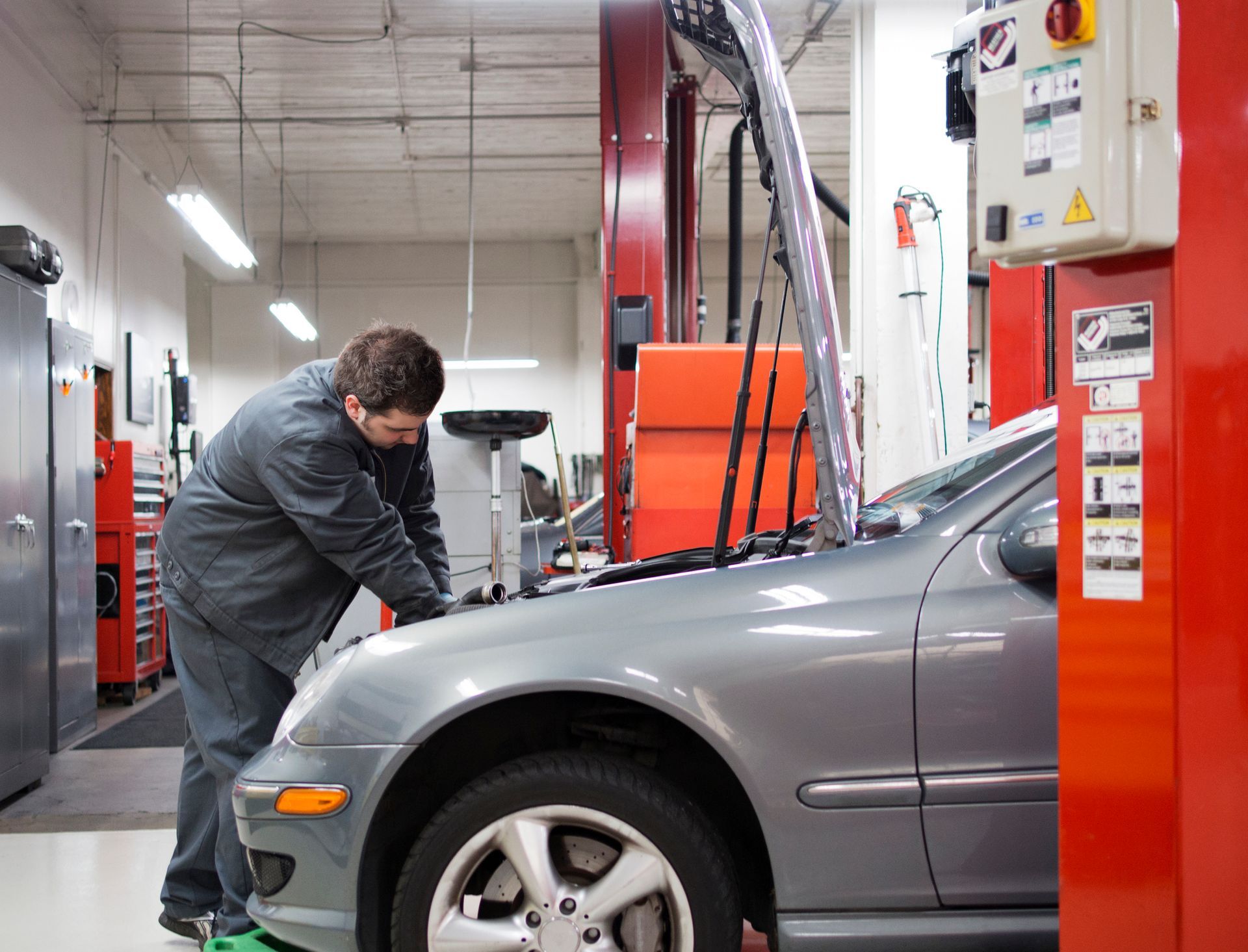 A mechanic performing Mercedes-Benz auto repair in a garage, surrounded by tools and equipment. A mechanic performing Mercedes-Benz auto repair in a garage, surrounded by tools and equipment.