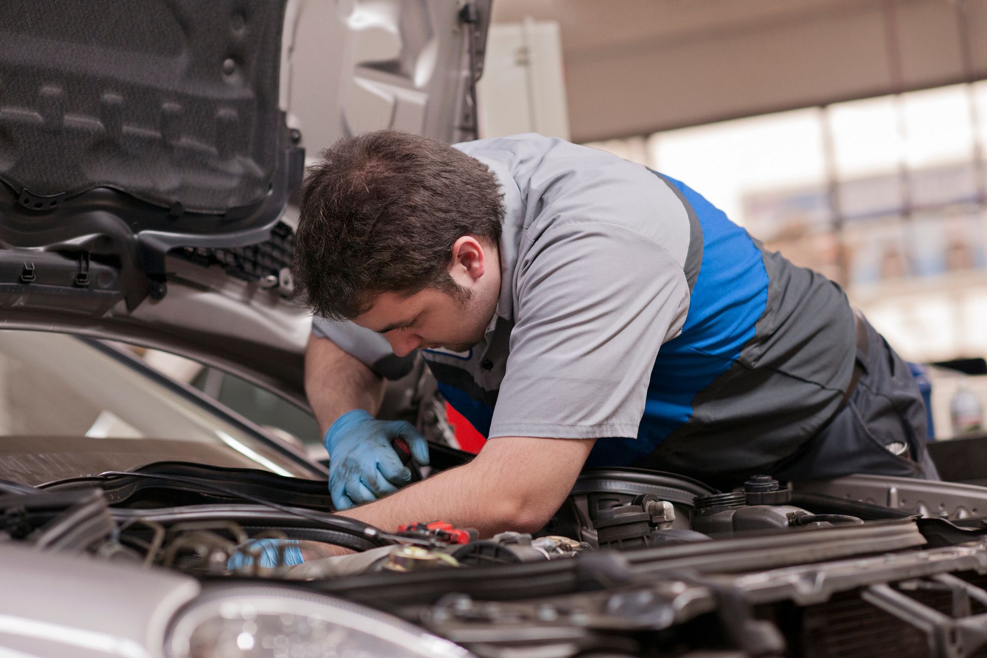 A mechanic inspecting a car's engine in a garage, showcasing Mercedes-Benz auto repair skills. A mechanic inspecting a car's engine in a garage, showcasing Mercedes-Benz auto repair skills.
