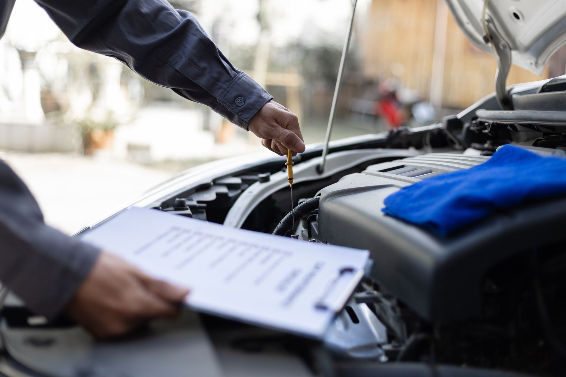 A mechanic inspects a Mercedes-Benz engine and checks oil levels during a routine car repair service