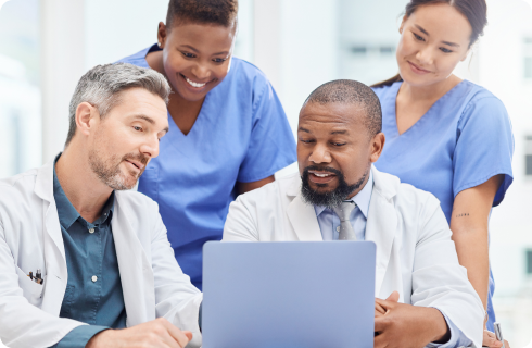 Um grupo de médicos e enfermeiros estão olhando para um laptop.