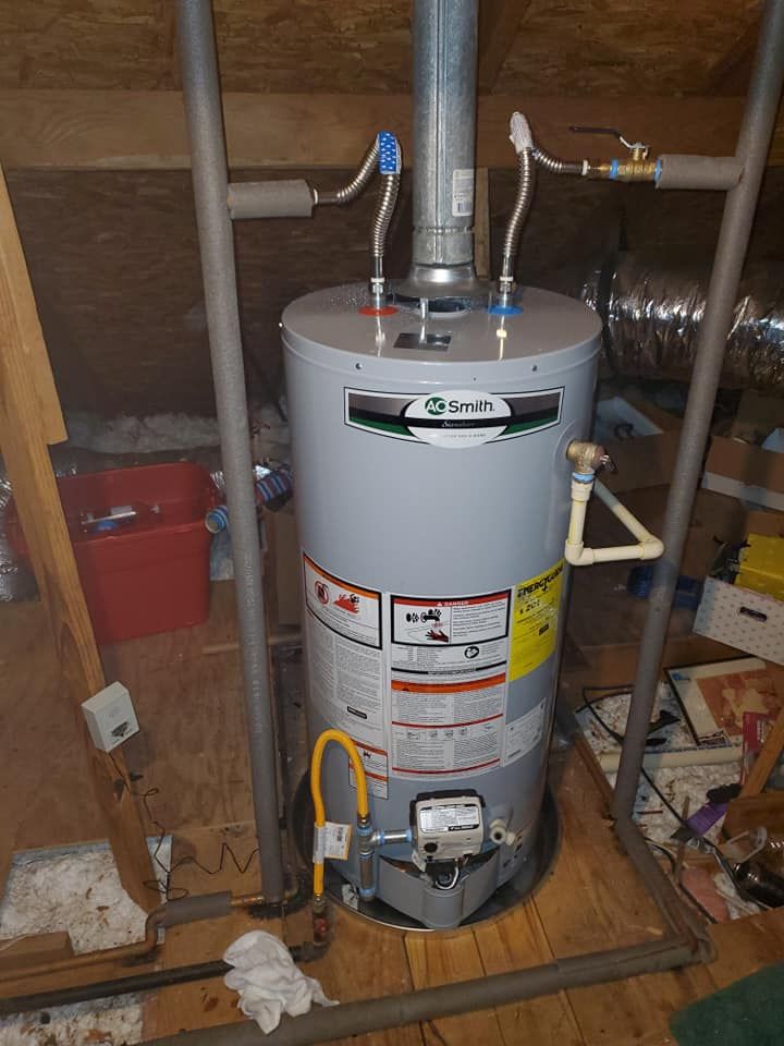Water heater in an attic with pipes, vent, and a yellow gas line, surrounded by a metal support frame.