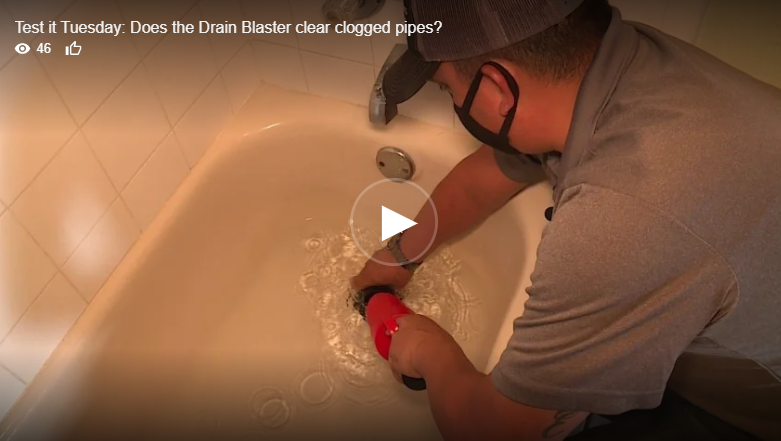 Man using a drain blaster in a white bathtub to clear a clog.