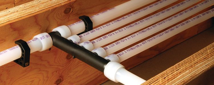 Plumbing pipes under a structure with tools, debris, and purple fabric.