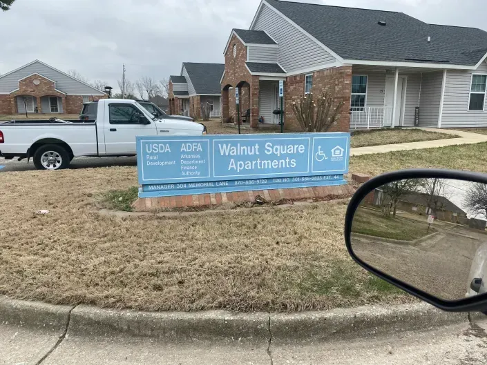 Walnut Square Apartments sign in front of residential buildings, with a white pickup truck parked nearby.