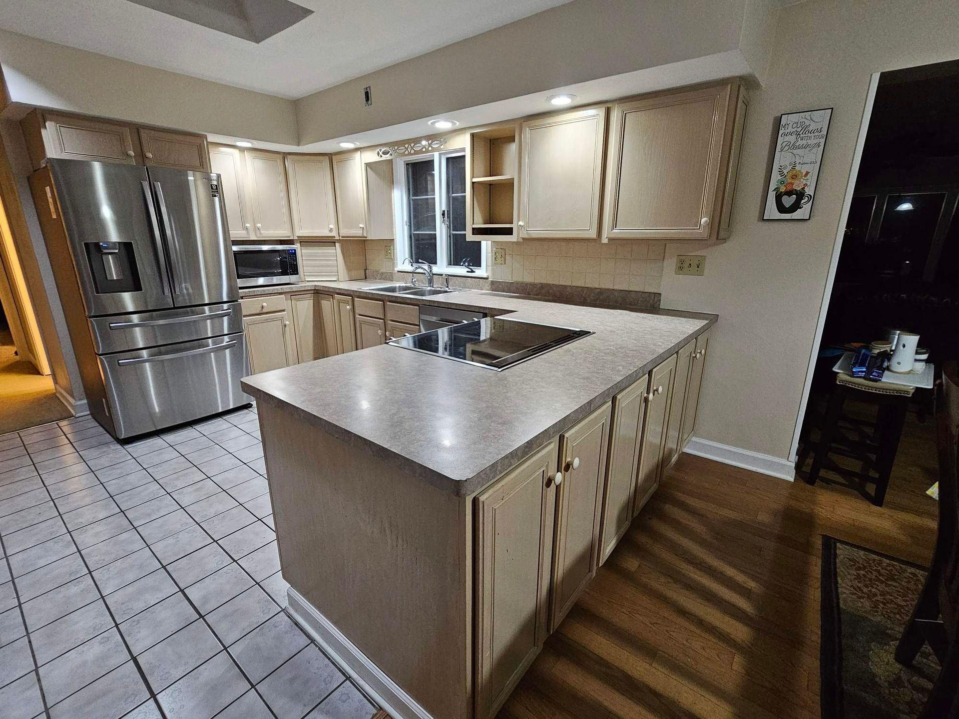 Kitchen with light-colored cabinets, stainless steel appliances, and a central island with a stovetop.