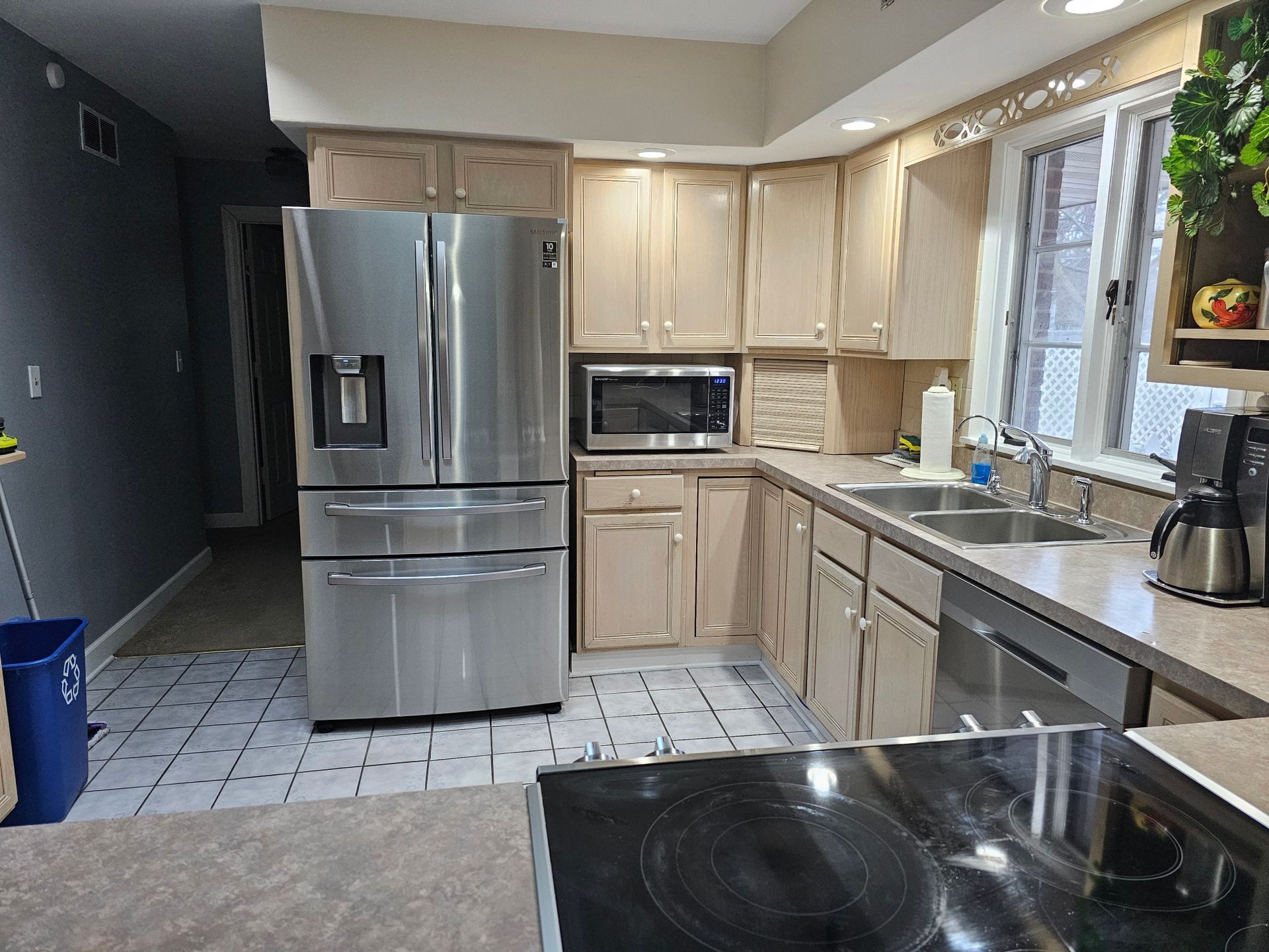 Kitchen with stainless steel refrigerator, light cabinets, microwave, sink, and an electric stove top.