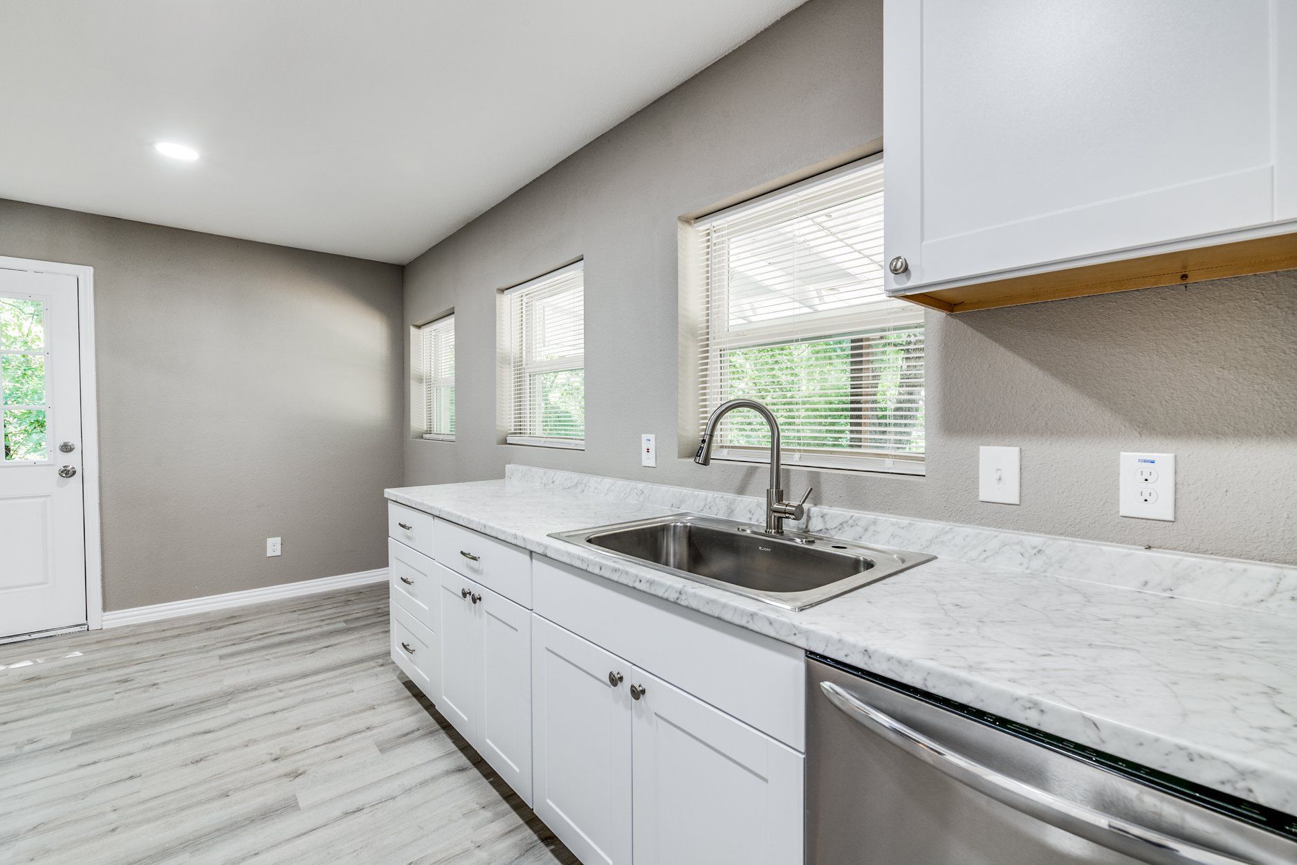 Kitchen with white cabinets, stainless steel sink, and gray walls.