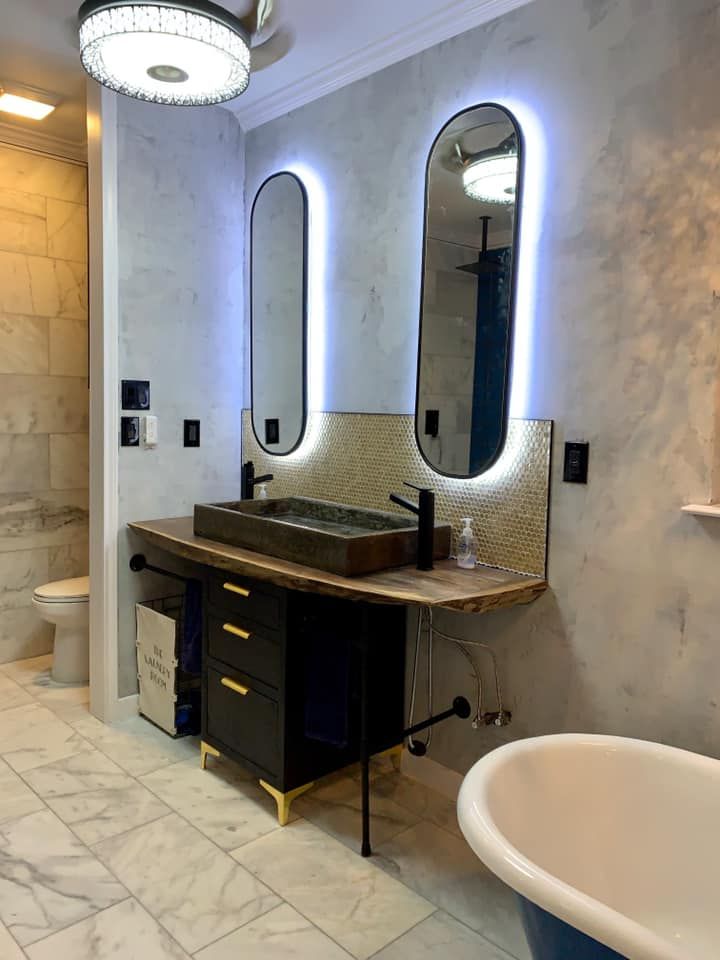 Bathroom with floating vanity, oval mirrors with LED lights, and a clawfoot tub.