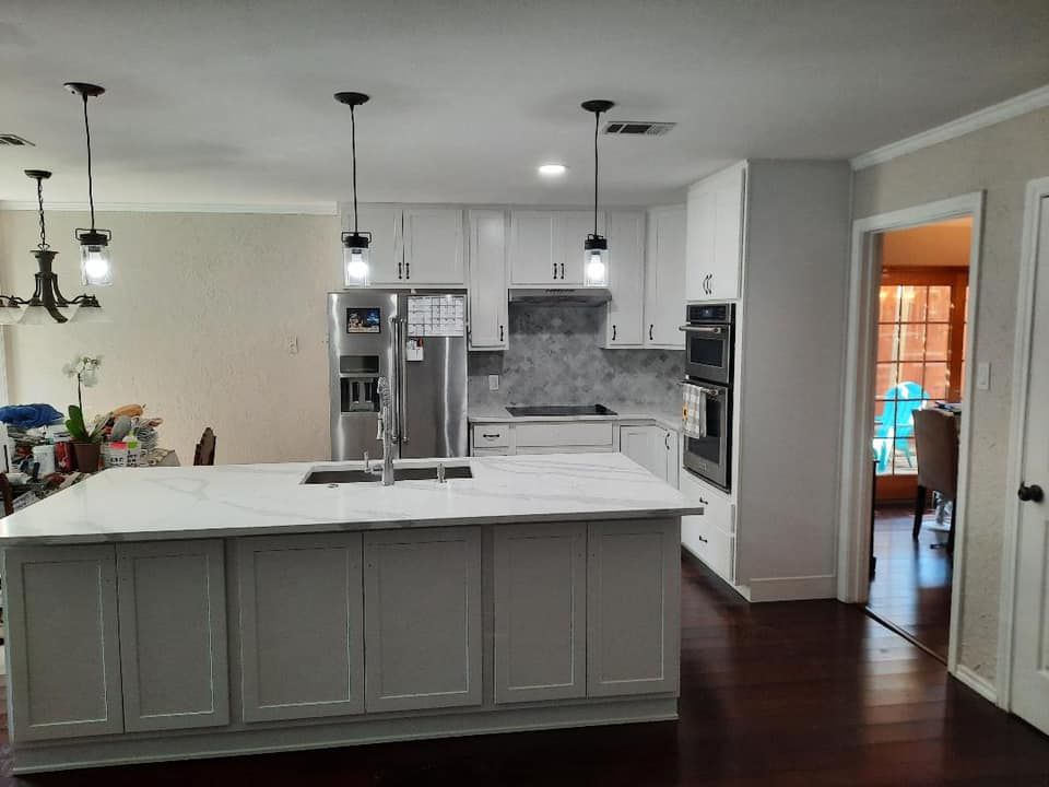White kitchen with island, stainless steel appliances, and dark hardwood floors.
